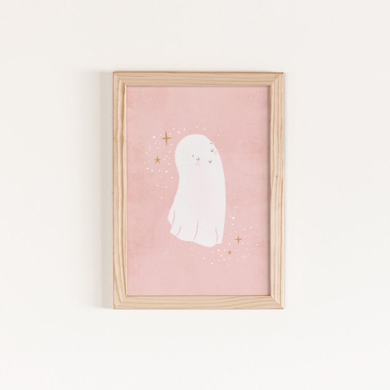 May include: A framed print of a white ghost with a pink background and gold glitter. The ghost has a cute, friendly expression.