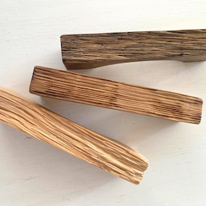 May include: Three wooden drawer pulls in various shades of brown. The pulls are made of reclaimed wood and have a rustic, farmhouse style.