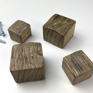 May include: Four rustic wooden drawer pulls with a square shape and a dark brown finish. The pulls have a rough, textured surface and are made from reclaimed wood.