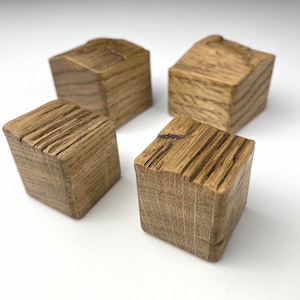 May include: Four small wooden cubes with a rustic, brown finish. The cubes have a natural wood grain pattern and are made from reclaimed wood.
