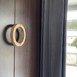 May include: A wooden cabinet door with a light brown circular door handle.