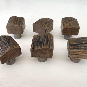 May include: Six rustic wooden knobs with a dark brown finish. The knobs have a square shape with rounded edges and a slightly irregular surface.