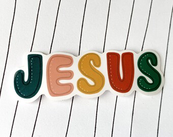May include: A sticker with the word "JESUS" in colorful, bubble-like letters. The letters are outlined in white and have a white background.