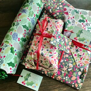 May include: A set of four Christmas gift wrapping papers with a variety of patterns. The papers feature geometric shapes, holly leaves, and the words "Merry Christmas".