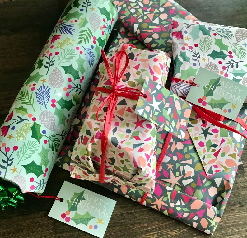 May include: A set of four Christmas gift wrapping papers with a variety of patterns. The papers feature geometric shapes, holly leaves, and the words "Merry Christmas".