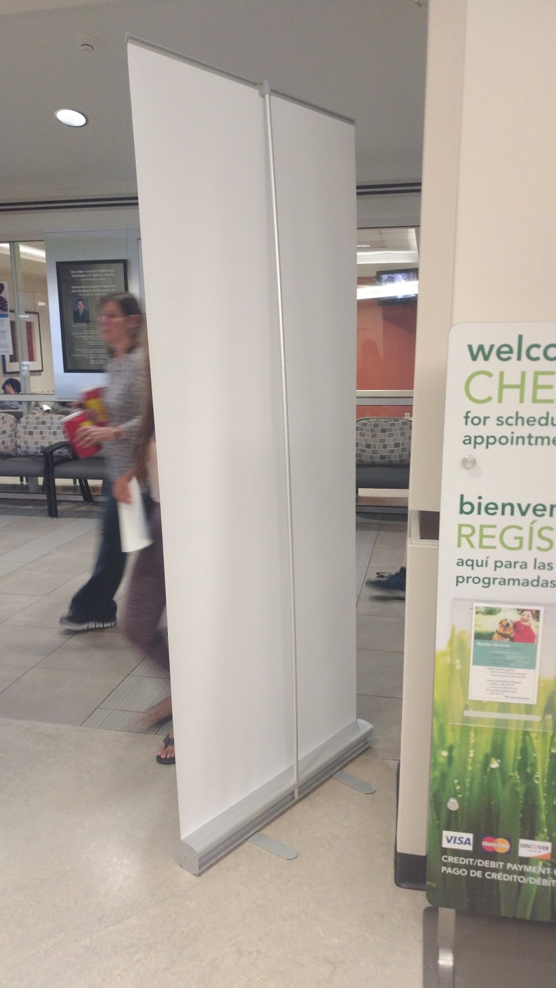 May include: A white retractable banner stand with a green and white sign that says "Welcome to CHE for scheduled appointments. Bienvenidos a REGIS aqui para las programadas. VISA CREDIT/DEBIT PAYMENT PAGO DE CR&Eacute;DITO/DEBIT".