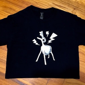 May include: Black t-shirt with a white graphic of a stylized deer with lightning bolts around it.