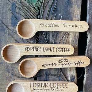 May include: Four wooden coffee scoops with different engraved sayings. The sayings are "No coffee. No workee.", "PEACE LOVE COFFEE", "mama needs coffee", and "I DRINK COFFEE for your protection".