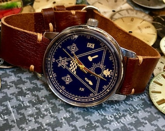 Reloj de pulsera de hallazgo raro con esfera azul masónica, correa de cuero y símbolo masónico.