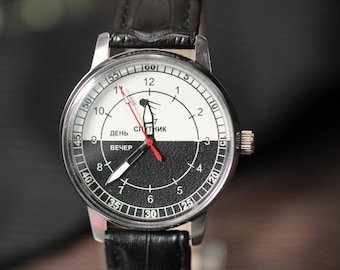 May include: A vintage wristwatch with a black leather band. The watch face is split into black and white halves, with the text "ДЕНЬ" and "ВЕЧЕР" visible. The watch has a red second hand and a silver-colored case.