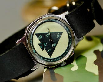 Reloj de pulsera con esfera triangular masónica, correa de piel y símbolo masónico.