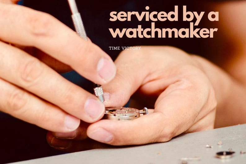 May include: A watchmaker is shown servicing a watch. The image includes the text "serviced by a watchmaker" and "TIME VICTORY". The watch is being worked on with a small tool.