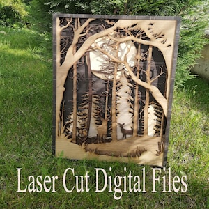 May include: Laser cut wooden wall art featuring a moonlit forest scene with two deer. The art is framed in a dark wood frame.