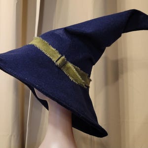 May include: A dark blue felt wizard hat with a wide brim and a green ribbon tied around the crown.