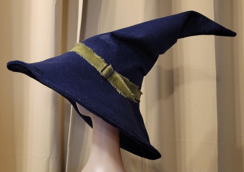 May include: A dark blue felt wizard hat with a wide brim and a green ribbon tied around the crown.