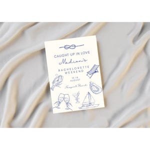 May include: A white card with blue text and illustrations announcing a hen do for Madison in Newport Beach, California from 10-14 August. The card features nautical themed illustrations like a sailboat, a seashell, a lobster, and a beach chair.