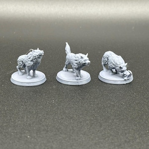 May include: Three gray 3D printed wolf figurines on round bases. The wolves are in different poses, one is standing, one is sitting, and one is lying down.