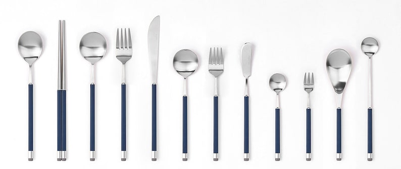 May include: A set of silver cutlery with blue handles, including a knife, fork, spoon, and chopsticks.