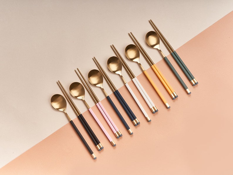May include: A set of ten gold chopsticks and spoons with colored handles. The handles are pink, black, white, yellow, and green.