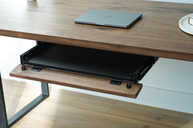 May include: A wooden desk with a pull-out keyboard tray and a laptop on top. The desk has a dark brown finish and a black metal frame. The keyboard tray is made of wood and black metal.