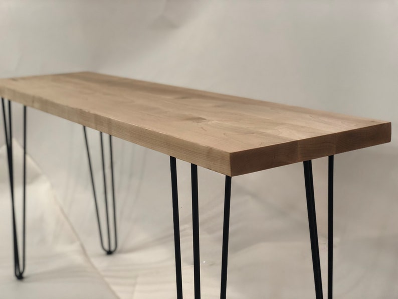 May include: A light wood console table with four black hairpin legs.