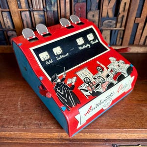 May include: A vintage Arithmetic Quiz toy in red and blue, with a black panel for calculations. It features addition, subtraction, multiplication, and division. The toy has illustrations of a teacher and students. The text on the toy reads "Arithmetic Quiz".