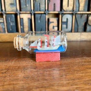 Miniatur Schiff in einer Flasche auf Ständer. Winziges Segelboot in einer Glasflasche