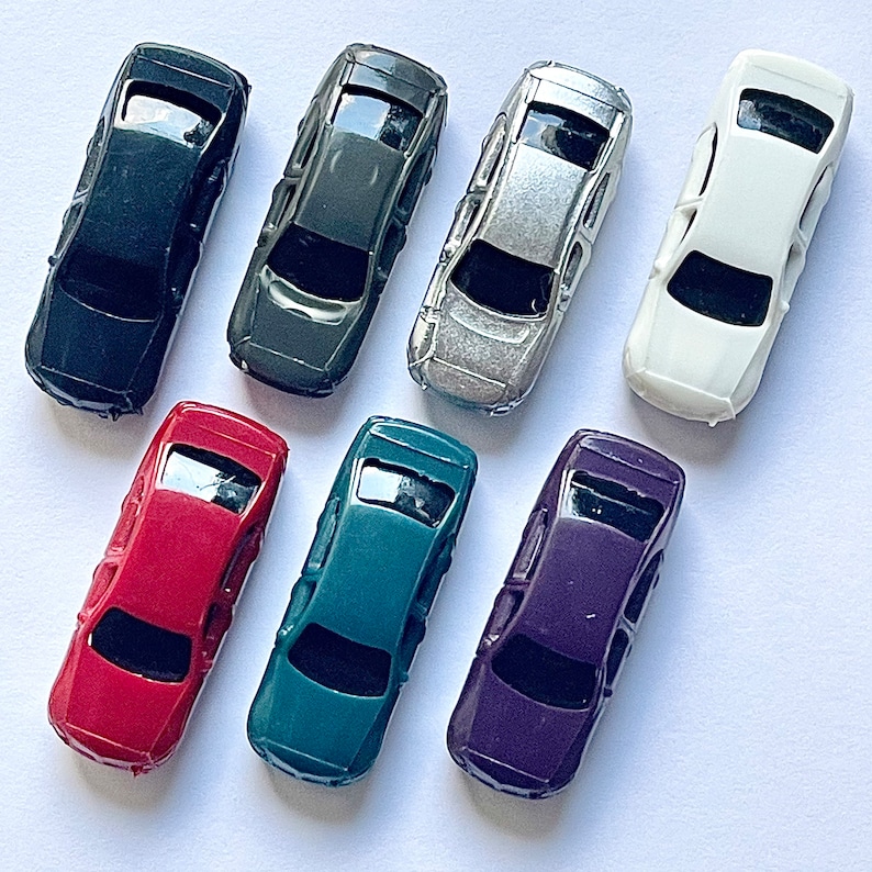 May include: Set of ten miniature toy cars in various colors, including black, dark green, silver, white, red, teal, and purple. The cars are all the same size and shape, with a classic sedan design.