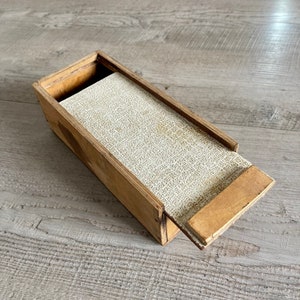 May include: A wooden box with a sliding lid. The box is open and the inside is lined with a white fabric.