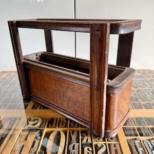 Peut inclure: Un casier rectangulaire en bois avec une finition brun foncé, doté d'un compartiment de rangement profond et d'un cadre supérieur ouvert soutenu par quatre montants verticaux. La structure présente un grain de bois visible et des fixations métalliques.