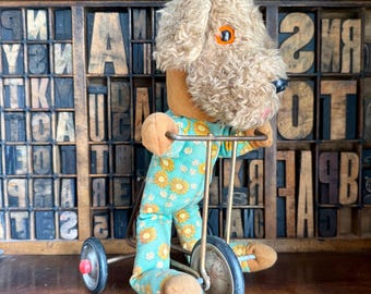 Vintage plush dog riding a bicycle