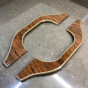 May include: Two wooden trim pieces with a gold trim. The trim pieces are shaped like a curved line with a rounded end.