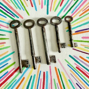May include: Five antique metal skeleton keys of varying lengths and designs, each featuring a circular bow and a distinct bit, arranged in a row against a white background decorated with radiating lines of various bright colours.