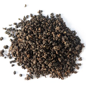 May include: A close-up of a pile of loose leaf black tea. The tea leaves are small and dark brown in color.