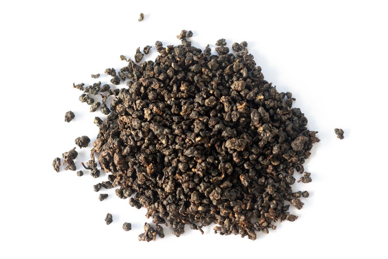 May include: A close-up of a pile of loose leaf black tea. The tea leaves are small and dark brown in color.