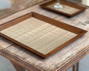 Può includere: Un vassoio rettangolare in legno con un motivo intrecciato a spina di pesce sul fondo. Il vassoio è in legno scuro e ha una finitura naturale.