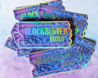 May include: A stack of rectangular stickers shaped like movie tickets with scalloped edges. The stickers feature a holographic finish with a blue and purple grid pattern and the text BLOCKBUSTER VIDEO printed in a bold, iridescent font.