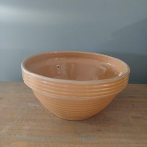 May include: A pale yellow ceramic mixing bowl with a ribbed design. The bowl has a small hole in the bottom.