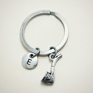 Puede incluir: Llavero de plata con un dije de la letra E y un dije de pipa.