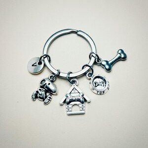 May include: Silver keychain with a dog bone, dog house, dog bowl, and a letter A charm. The dog house charm says "Top Dog".