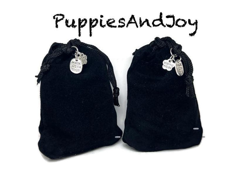 May include: Two black velvet drawstring pouches with silver charms that say "Made with Love" and "Hand Made".