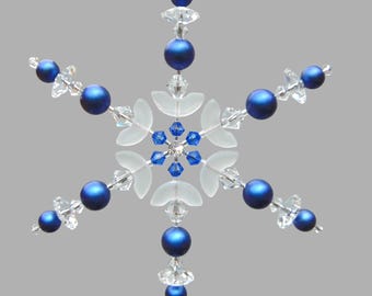 May include: A blue and clear crystal snowflake ornament with a beaded design. The snowflake has six points and is decorated with blue beads and clear crystals.