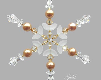 May include: Gold snowflake ornament with clear crystal beads and white glass accents. The snowflake is suspended from a gold wire.