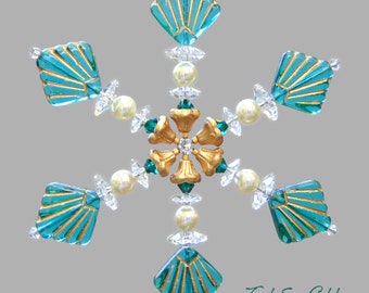 May include: Teal and gold snowflake ornament with a crystal center and a beaded border.  The snowflake is made of glass and has a delicate, intricate design.  The ornament is perfect for adding a touch of elegance to your holiday decor.