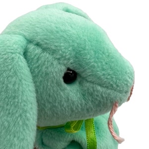 May include: A plush green bunny with a pink nose and a green ribbon around its neck.