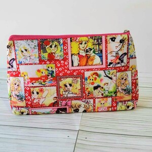 May include: Pink zippered pouch with a colorful print of cartoon girls in various scenes. The print features a red, white, and pink color scheme.