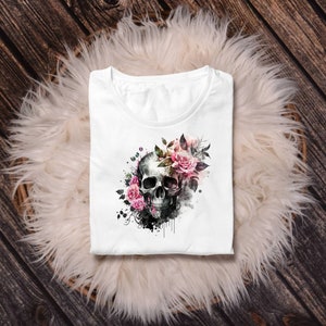 May include: White t-shirt with a black and white skull graphic surrounded by pink and white watercolor flowers.