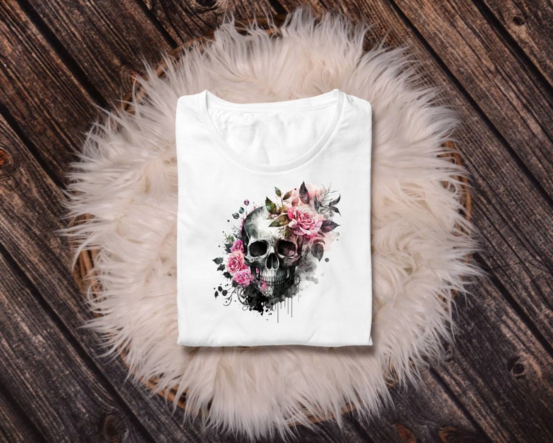 May include: White t-shirt with a black and white skull graphic surrounded by pink and white watercolor flowers.