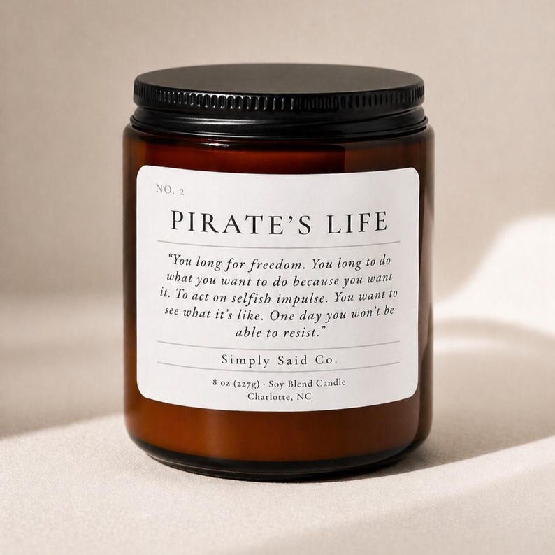 May include: A brown glass jar candle with a black lid. The label reads "PIRATE'S LIFE" with a quote and "Simply Said Co." The candle is 8 oz (227g) and is a soy blend.