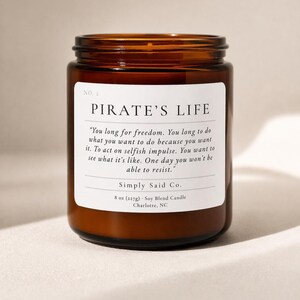May include: A brown glass jar candle with a white label that reads "PIRATE'S LIFE." The label includes a quote and the text "Simply Said Co." The candle is 8 oz (227g) and is a soy blend.